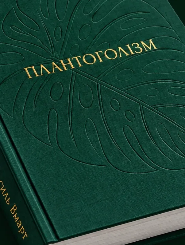 Зблизька: тканинна обкладинка з тисненим листком монстери і золотою назвою «ПЛАНТОГОЛІЗМ»